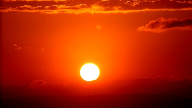 Cose up time lapse of the sun setting behind a mountain range against a orange sky background in full HD .在全高清的背景下，太阳下山的时间流逝视频素材