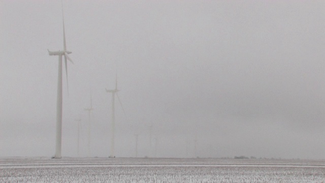 缩小镜头，风力涡轮机在一个被雪覆盖的领域视频素材