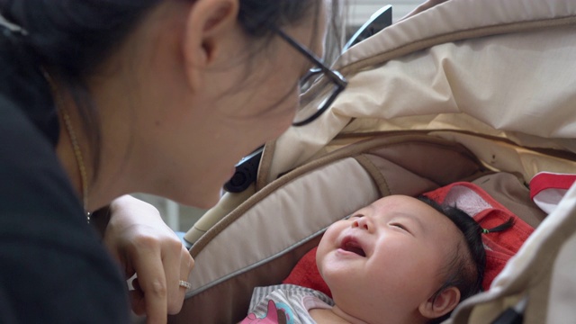 妈妈在婴儿车里笑着，开心地陪着女儿，手持相机拍4K。真正的生活视频素材