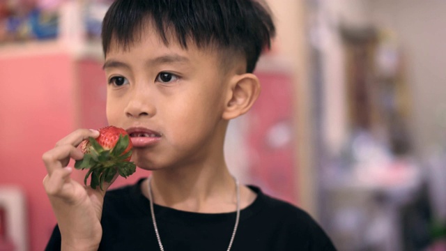 亚洲男孩在吃草莓视频素材