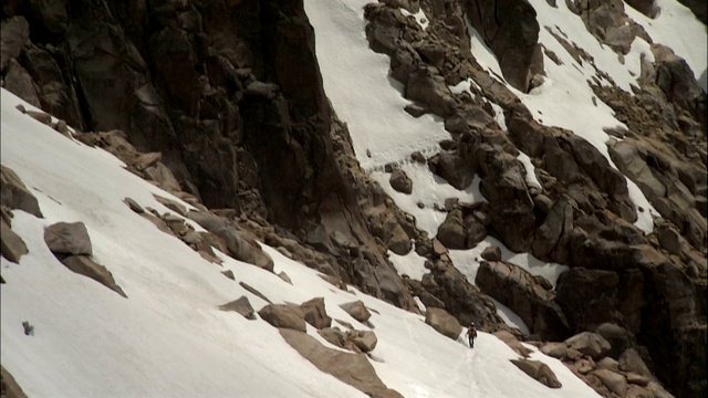 登山者跋涉在崎岖多雪的山坡上。视频素材