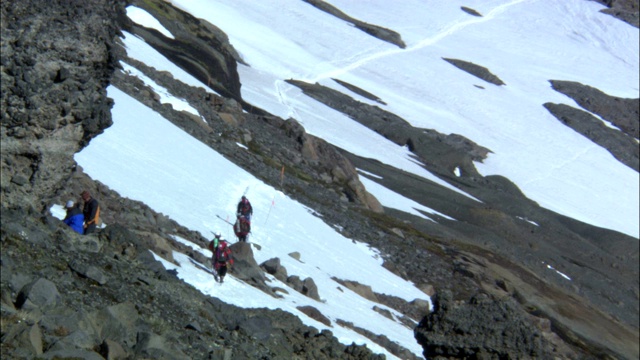 一队登山队员沿着崎岖多雪的山坡徒步旅行。视频素材