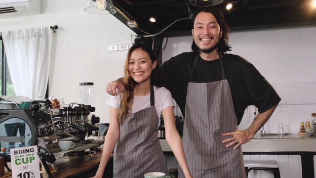 亚洲咖啡师小企业主合伙人微笑着看着相机在柜台酒吧在咖啡店。开创年轻人的事业。慢动作视频素材