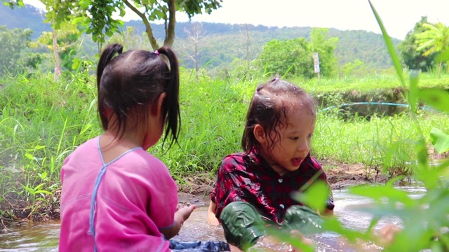 孩子们赤脚在溪水中玩耍，玩泥巴和沙子。视频素材