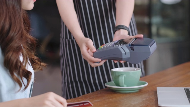 近距离亚洲女性顾客用信用卡支付给女服务生。小型企业的技术，食品和饮料业务，账单支付视频素材