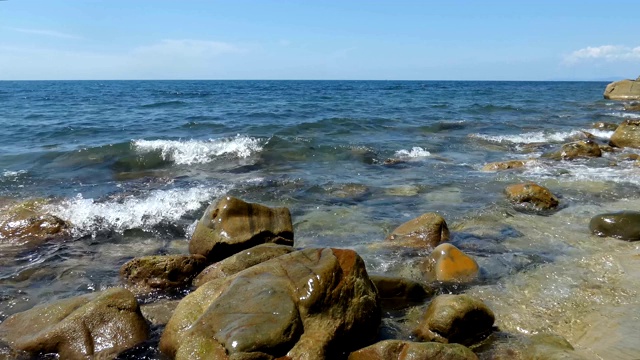 海浪拍打着海滩上的石头。后方有地平线的公海视频素材