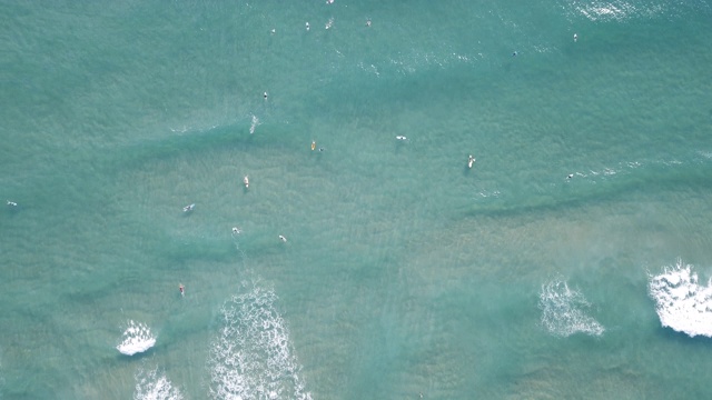 冲浪者在清澈的蓝色海洋中漂浮和捕捉海浪视频素材