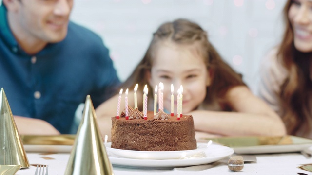 特写微笑的寿星吹12支生日蜡烛在豪华的房子。视频素材