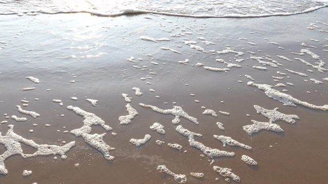 海浪在沙滩上形成白色的泡沫视频素材