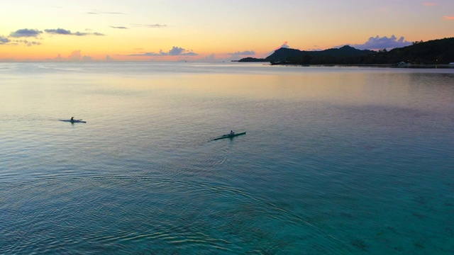 法国波利尼西亚的波拉波拉，在令人惊叹的夕阳下，人们在海上划艇，无人机向前飞行，倾斜然后从右到左转弯视频素材