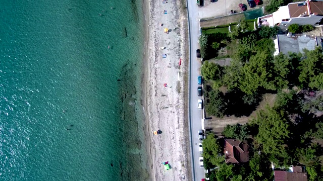 鸟瞰图的海岸线，清澈的绿松石海水和小海滩旁边的游客住宅，Siviri Halkidiki，希腊，由无人机向前移动视频素材