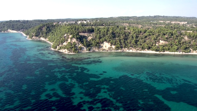 鸟瞰图的海岸线与小绿松石海滩下的岩石和树，Siviri Halkidiki，希腊，由无人机做圆周运动视频素材