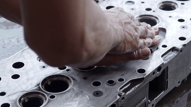 亚洲工人在清洗和抛光汽缸头时用砂纸和润滑油，维护发动机的概念。视频素材