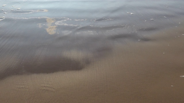 潮湿的沙滩上的沙子在海浪后干燥视频素材