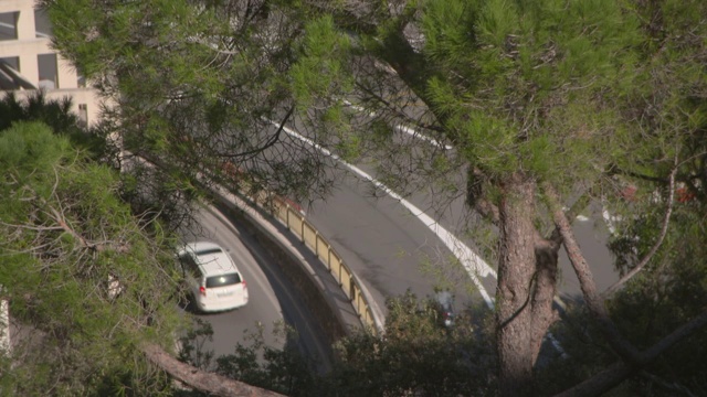 航拍:在阳光明媚的日子里，摩纳哥蒙特卡洛，一架无人机飞过街道，车辆穿过树木视频素材