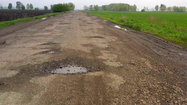 糟糕的乡村道路，雨后有许多坑、坑和水坑视频素材