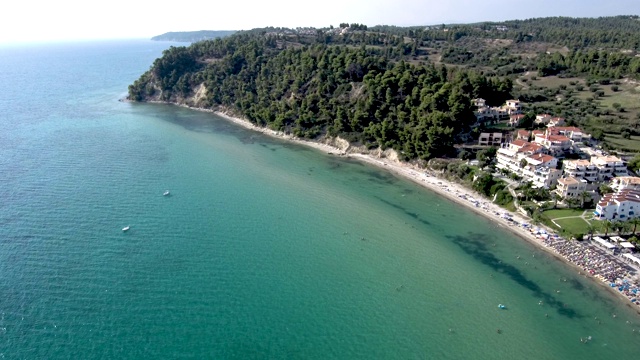 鸟瞰图的海岸线，清澈的绿松石海水和小海滩旁边的游客住宅，Siviri Halkidiki，希腊，由无人机向前移动视频素材