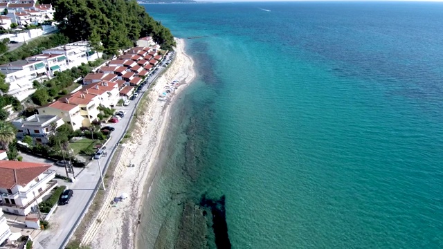 鸟瞰图的海岸线，清澈的绿松石海水和小海滩旁边的游客住宅，Siviri Halkidiki，希腊，由无人机向前移动视频素材