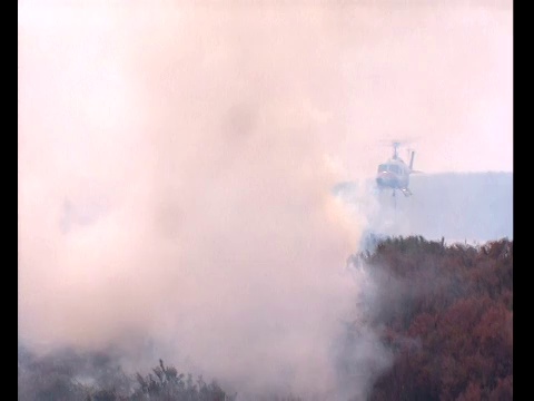 一架直升飞机穿过丛林大火产生的浓烟。视频素材