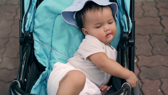 戴着蓝帽子的婴儿车上的小女孩视频素材