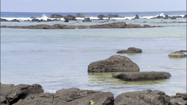 海浪冲刷着海滩附近的岩石海岸线和池塘。视频素材