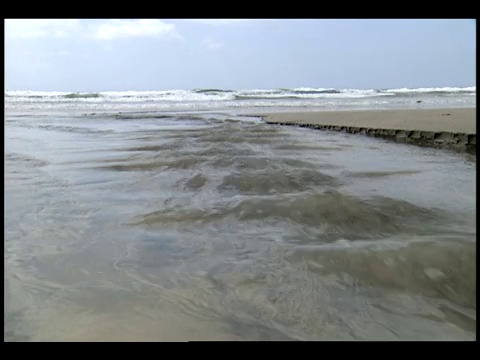 退潮时，海水沿着混凝土板侵蚀海滩。视频素材