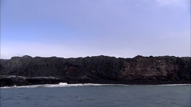 海浪冲击着坚硬的熔岩峭壁。视频素材