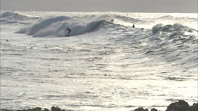 冲浪者在夏威夷海岸外的波浪中摇摆。视频素材