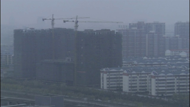 雾霾掩盖了城市的天际线，屋顶上的建筑起重机几乎看不见。视频素材