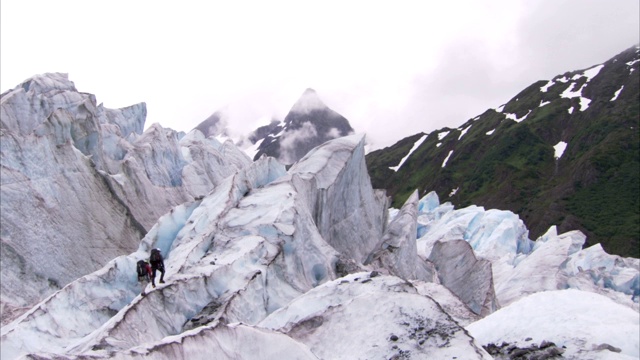 登山者徒步攀登朱诺冰原上的积雪冰川。视频素材