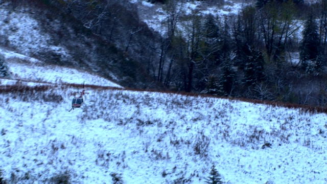 一架直升飞机低低地飞过白雪覆盖的山坡。视频素材