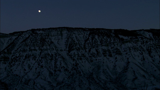 一轮满月在黄石国家公园的雪山上闪烁。视频素材