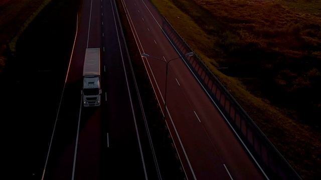 大型货车是移动的夕阳。空中拍摄的卡车在美丽的乡村道路在日落。鸟瞰图的半卡车在道路与日落的背景。视频素材