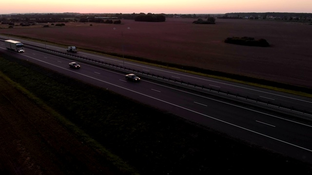 大型货车是移动的夕阳。空中拍摄的卡车在美丽的乡村道路在日落。鸟瞰图的半卡车在道路与日落的背景。视频素材