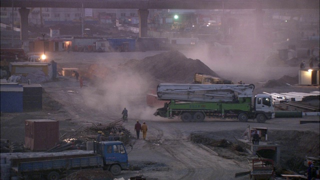 在上海虹桥国际机场，卡车和工人正在通过一个建筑工地。视频素材