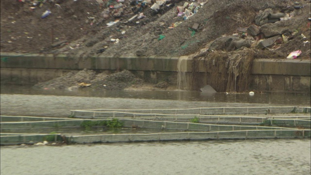 水从垃圾填埋场倾泻到一条浅河里。视频素材