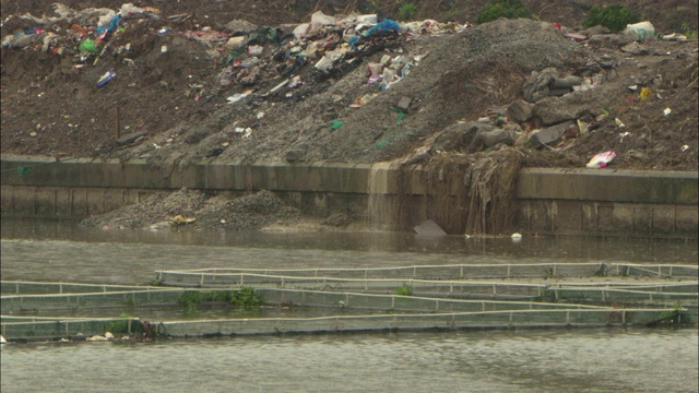 雨水从垃圾填埋场倾泻到河里。视频素材