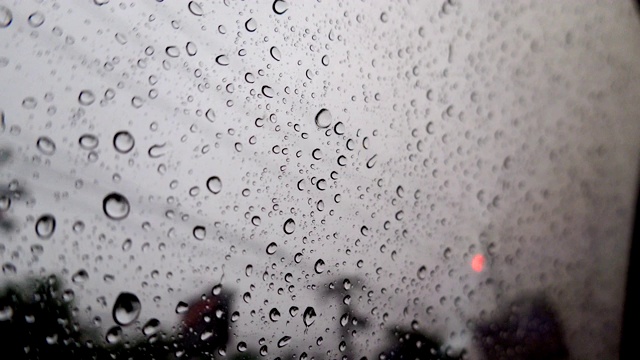 抽象模糊的雨，当汽车在道路中间的夜晚汽车尾灯反射雨滴在汽车的镜子视频素材