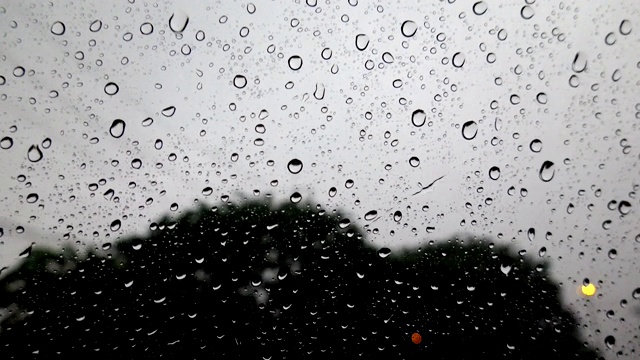 抽象模糊的雨，当汽车在道路中间的夜晚汽车尾灯反射雨滴在汽车的镜子视频素材