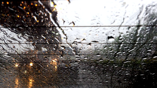 抽象模糊的雨，当汽车在道路中间的夜晚汽车尾灯反射雨滴在汽车的镜子视频素材