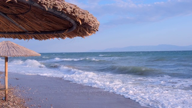 海景海洋和美丽的海景热带海滩透过茅草伞。空旷的沙滩上的背景清澈的绿松石海。节日的概念视频素材