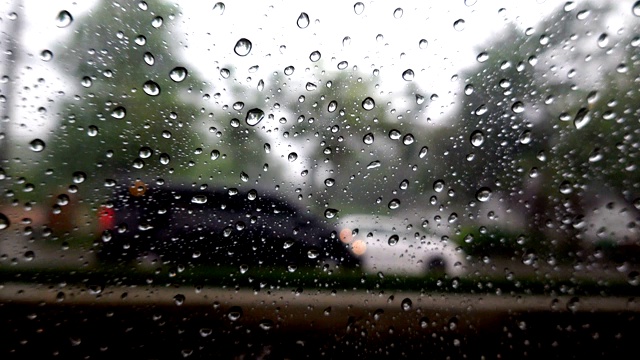 抽象模糊的雨，当汽车在道路中间的夜晚汽车尾灯反射雨滴在汽车的镜子视频素材