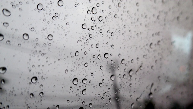 抽象模糊的雨，当汽车在道路中间的夜晚汽车尾灯反射雨滴在汽车的镜子视频素材