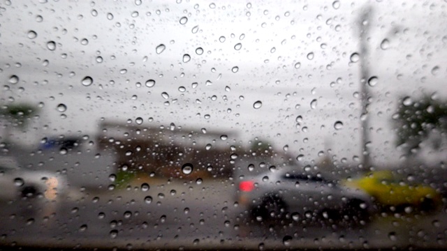 抽象模糊的雨，当汽车在道路中间的夜晚汽车尾灯反射雨滴在汽车的镜子视频素材