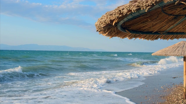 海景海洋和美丽的海景热带海滩透过茅草伞。空旷的沙滩上的背景清澈的绿松石海。节日的概念视频素材