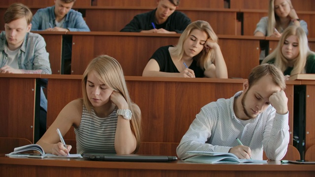 多民族学生在课堂上听讲师讲课，并在笔记本上写作。聪明的年轻人在大学学习视频素材