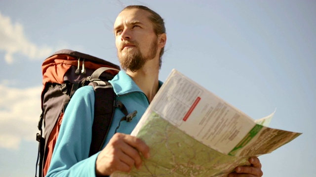 一个年轻的白种人手里拿着一张地图在登山旅行。视频素材