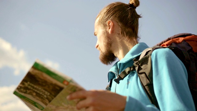 一个年轻的白种人手里拿着一张地图在登山旅行。视频素材