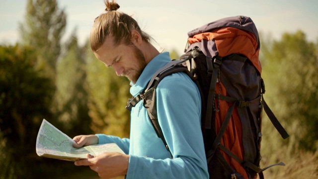 一个年轻的白种人手里拿着一张地图在登山旅行。视频素材