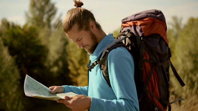 一个年轻的白种人手里拿着一张地图在登山旅行。视频素材